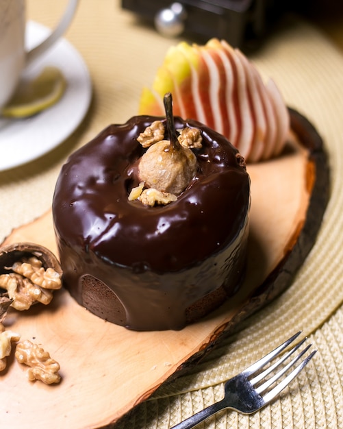 Torta della pera sul bordo di legno con il cioccolato delle noci e la vista laterale della frutta fresca