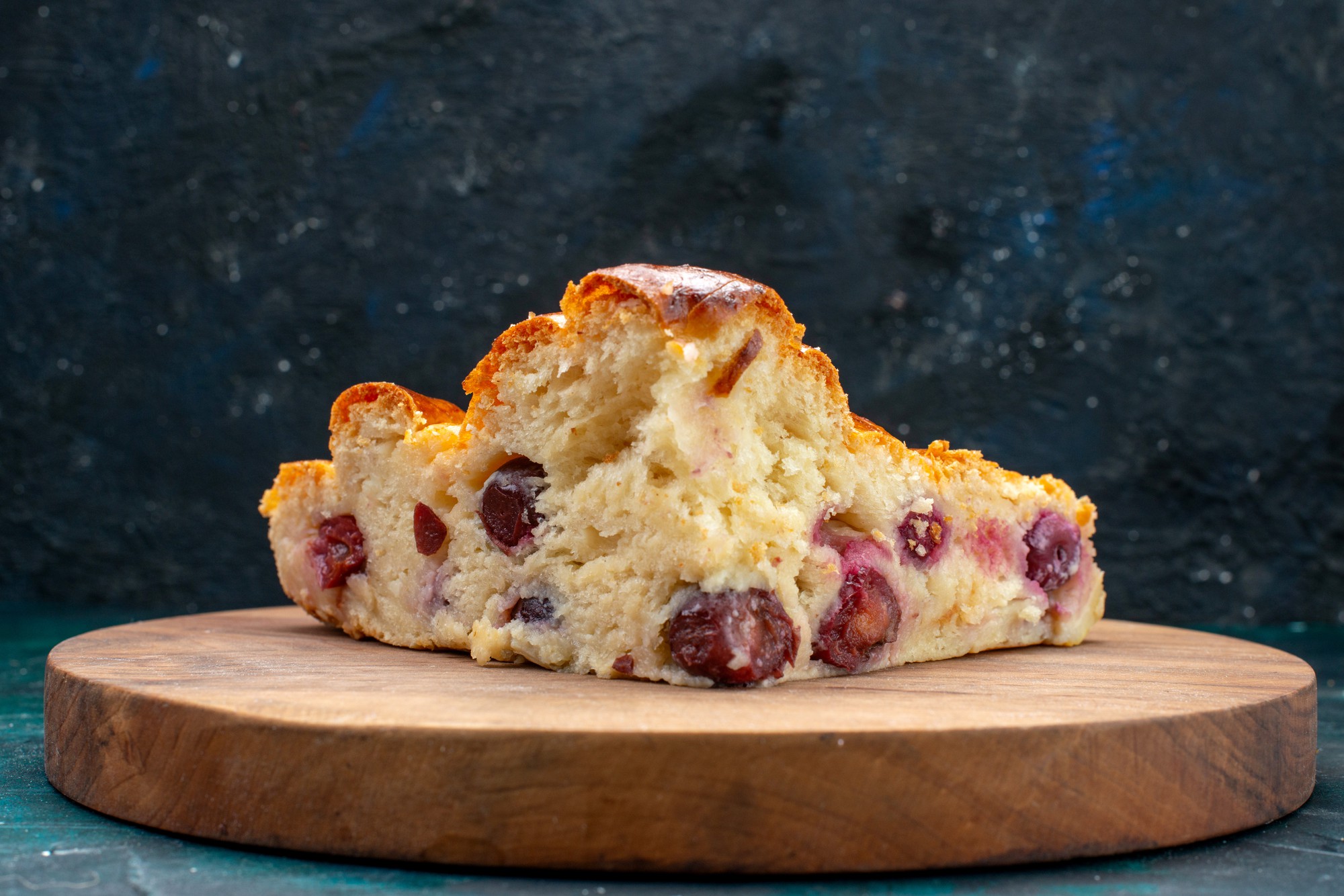 torta di ciliegie con zucchero in polvere e ciliegie all'interno su tè dolce alla frutta blu scuro