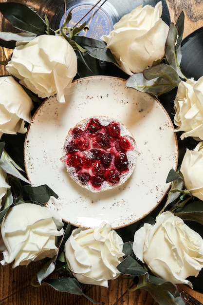 Torta di ciliegie vista dall'alto su un piatto con rose bianche in un cerchio