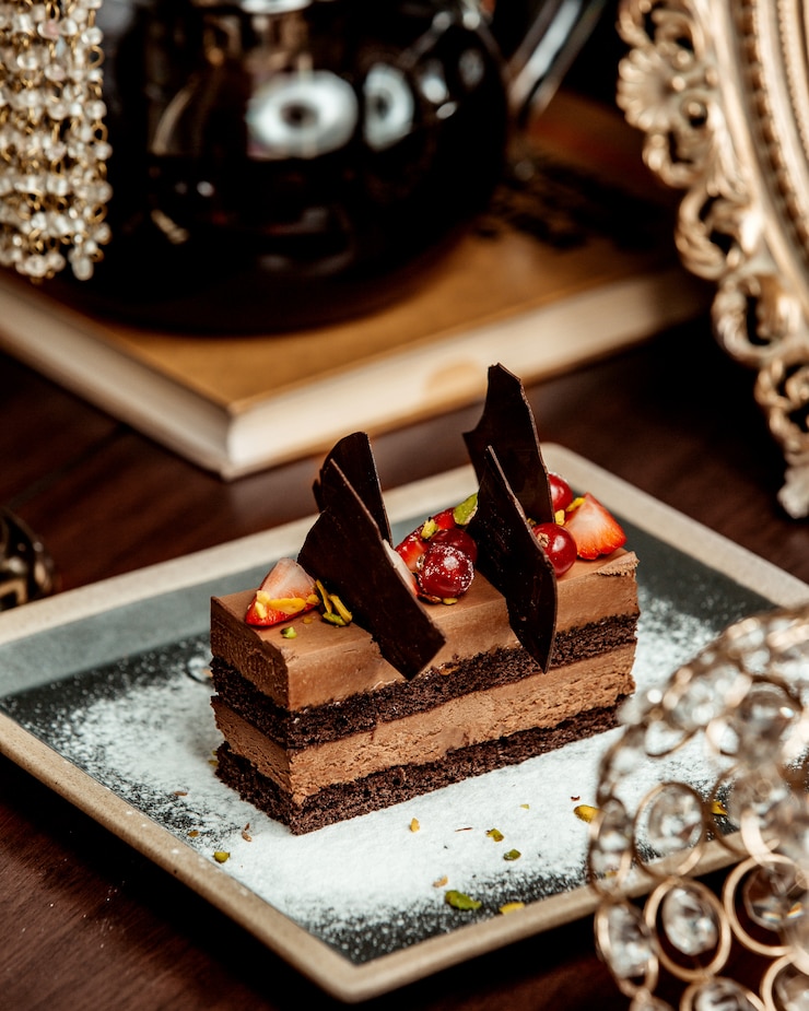 Foto gratuito torta di cioccolato porzionata guarnita con bacche e cioccolata