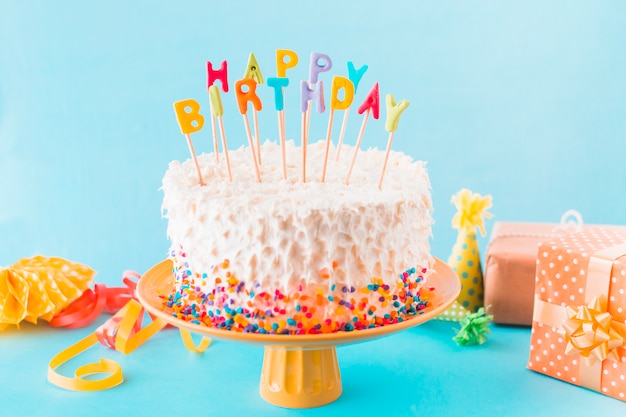 Torta di compleanno con regalo e accessori su sfondo blu