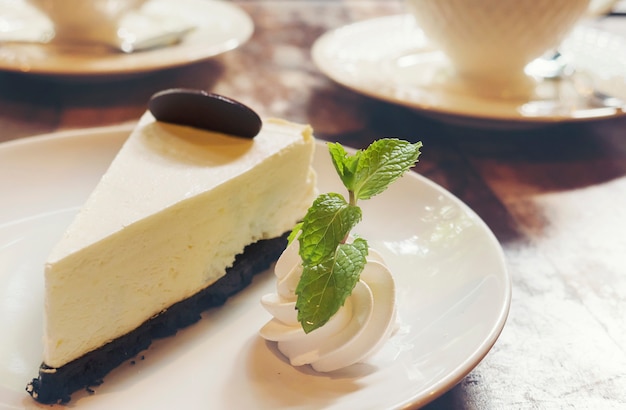 Torta di formaggio con la tazza di caffè caldo nella caffetteria