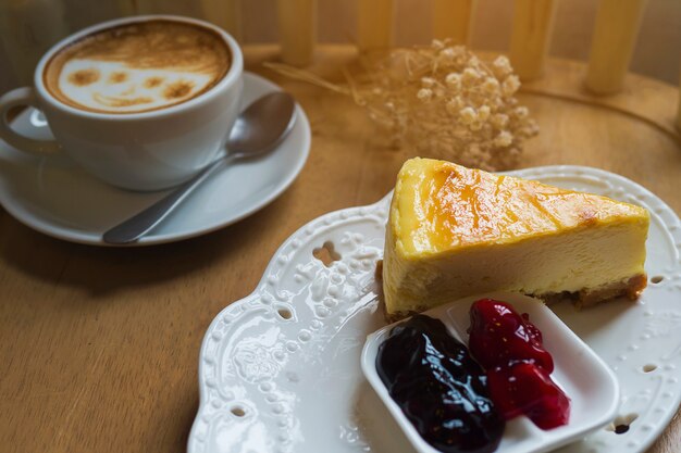 Torta di formaggio con la tazza di caffè caldo sulla tavola di legno