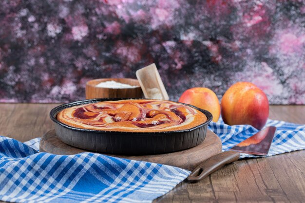 Torta di fragole servita con pesche rosse e gialle.