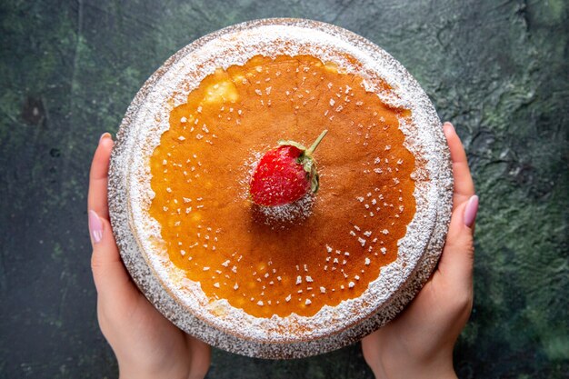 Torta di miele squisita vista dall'alto con zucchero in polvere sulla superficie scura del bordo di legno rotondo