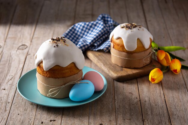 Torta di Pasqua tradizionale, uova colorate e tulipani su tavola di legno.