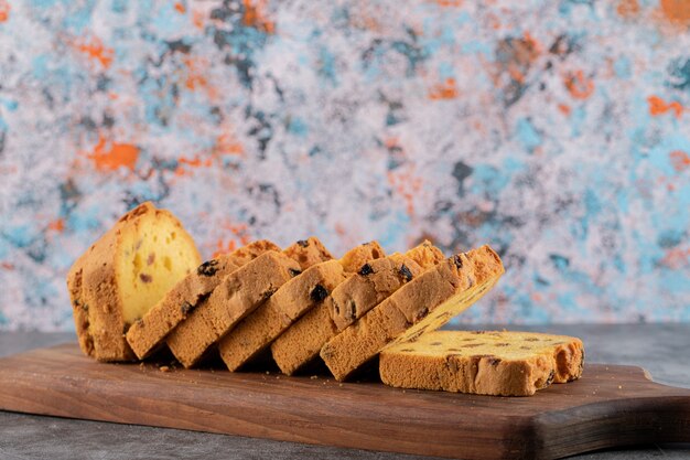 Torta di roulette fatta in casa a fette sul tagliere di legno sopra il tavolo grigio.