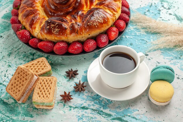 Torta dolce gustosa vista frontale con cialde di fragole rosse fresche e tazza di tè sulla superficie blu