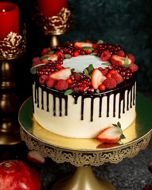 Torta gocciolante al cioccolato con torta bianca guarnita con frutti di bosco