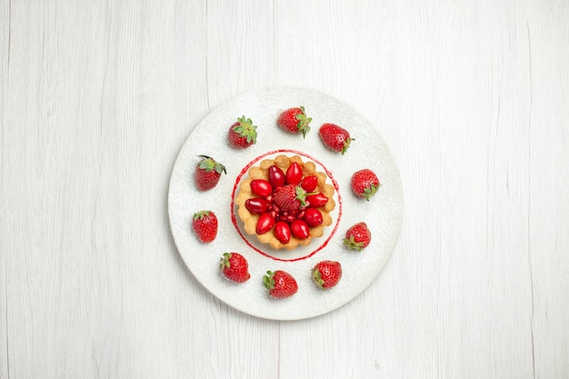 Torta gustosa vista dall'alto con frutta all'interno del piatto sulla scrivania bianca