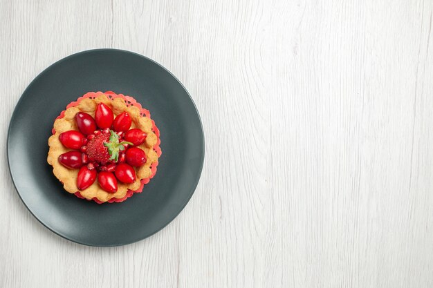 Torta gustosa vista dall'alto con frutta fresca all'interno del piatto sulla scrivania bianca