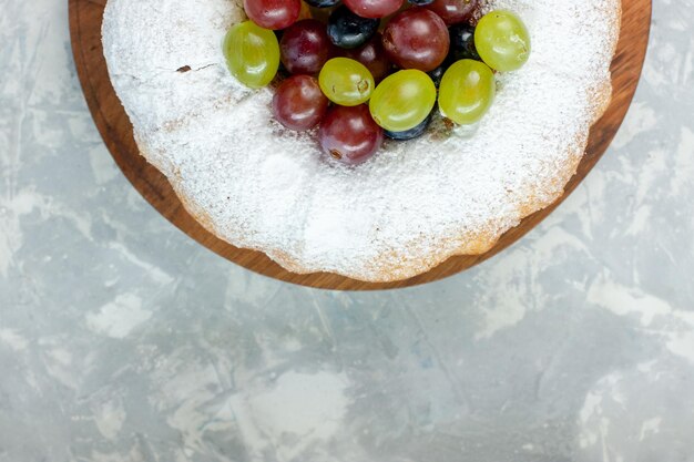 Torta in polvere vista dall'alto deliziosa torta al forno con uva fresca su superficie bianca