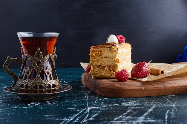 Torta Medovic servita con un bicchiere di tè su tavola di legno.