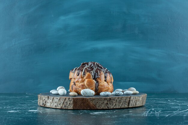 Torta ricoperta di cioccolato e caramelle rocce su una tavola sul blu.