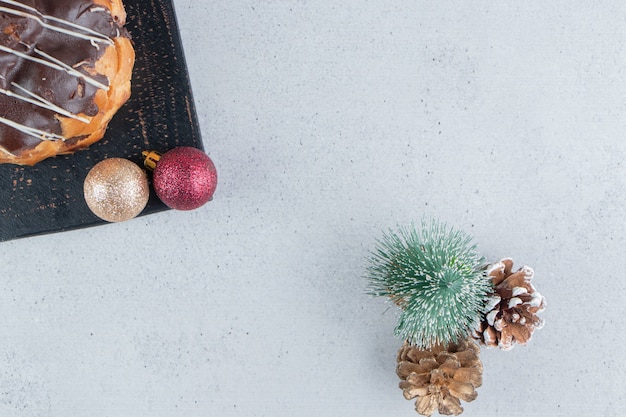 Torta ricoperta di cioccolato su una tavola accanto agli ornamenti di Natale su fondo di marmo.