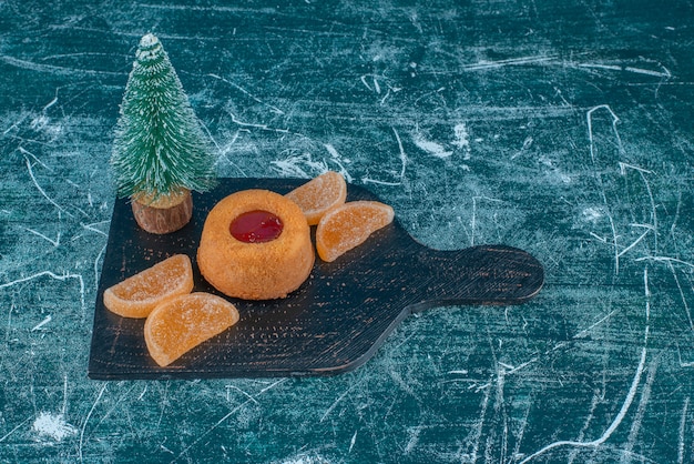 Torta ripiena di gelatina, marmellate e una figurina di albero su un bordo nero su sfondo blu. Foto di alta qualità