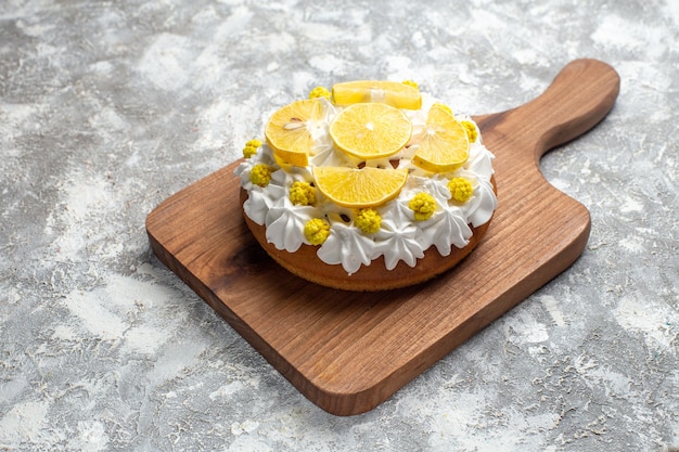 Torta vista dal basso con crema bianca e fette di limone sul tagliere sul tavolo grigio