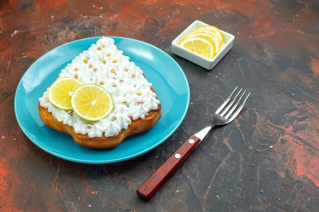 Torta vista dal basso con limone su piastra blu Fette di limone nella forchetta della ciotola su sfondo rosso scuro