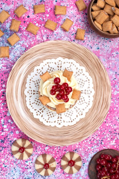 Torta vista dall'alto con crema insieme a biscotti e mirtilli rossi sullo sfondo colorato torta biscuir zucchero colore dolce