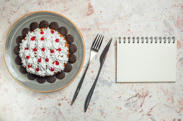 Torta vista dall'alto con crema pasticcera e forchetta al cioccolato e taccuino con coltello da cena