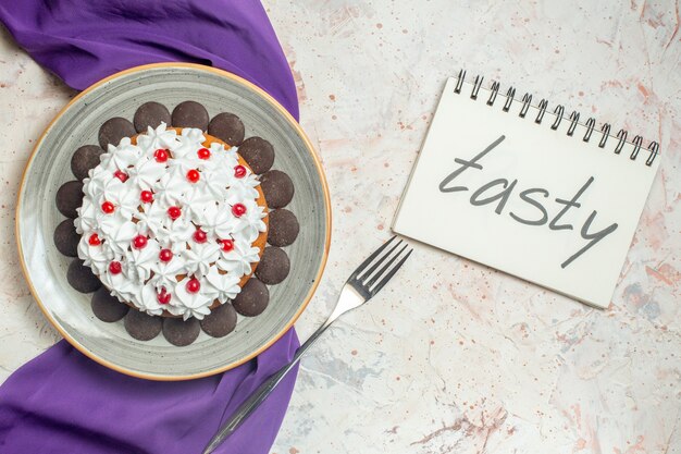 Torta vista dall'alto con crema pasticcera su piatto forchetta scialle viola gustosa scritta sul taccuino