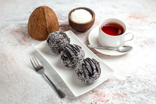 Torte al cioccolato di vista frontale con la tazza di tè sul biscotto dolce dello zucchero del biscotto della torta di cioccolato di superficie bianca