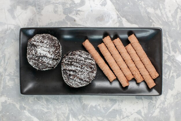 Torte al cioccolato vista dall'alto con biscotti tubo dolce all'interno della banda nera su superficie bianca