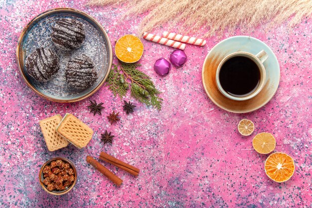 Torte al cioccolato vista dall'alto con cialde e tazza di tè su rosa chiaro