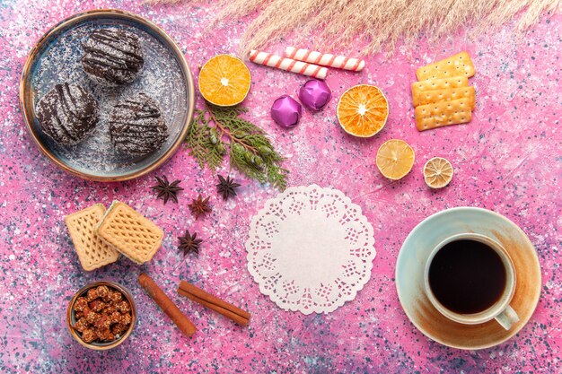 Torte al cioccolato vista dall'alto con cialde e tazza di tè sulla scrivania rosa