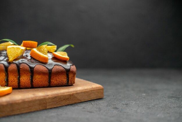 Torte morbide sul tagliere e arance tagliate con foglie sul tavolo scuro