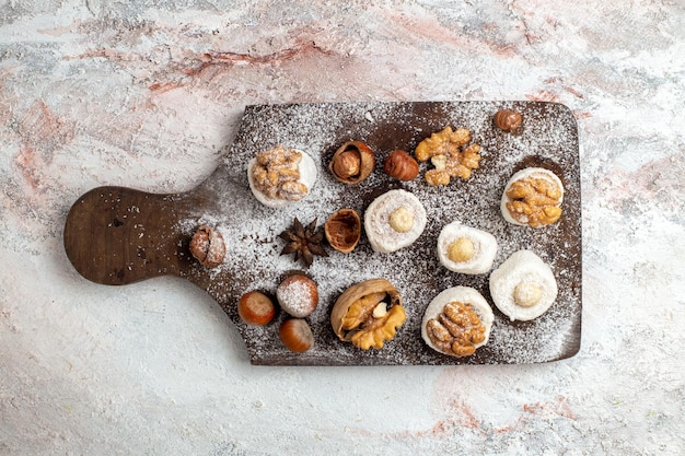 Torte vista dall'alto con noci e nocciole su superficie bianca