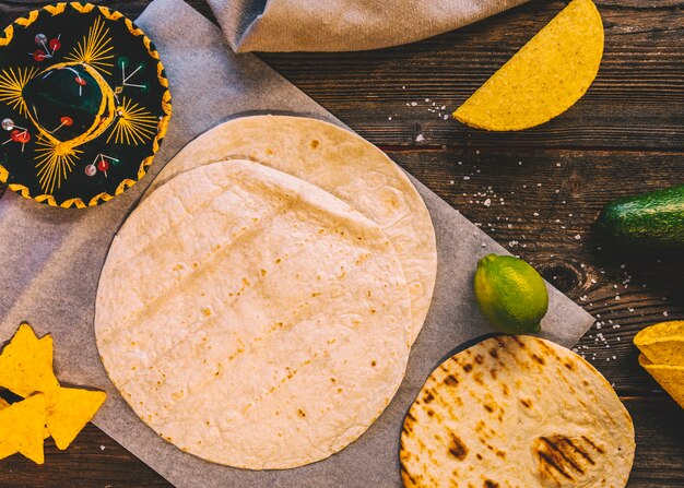 Tortilla di grano messicano; gustosi nachos e limoni sul tavolo in legno con cappello messicano