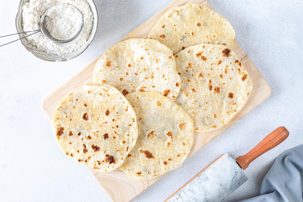 Tortillas di grano fatte in casa pita tortilla pita con ingredienti per cucinare su un tavolo bianco Vista dall'alto