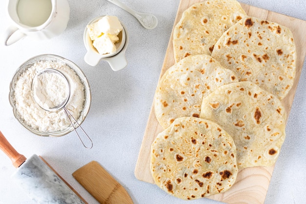 Tortillas di grano fatte in casa pita tortilla pita con ingredienti per cucinare su un tavolo bianco Vista dall'alto