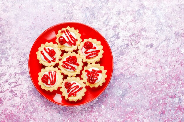 Tortine con ripieno di cioccolato bianco e marmellata di frutti di bosco in cima.