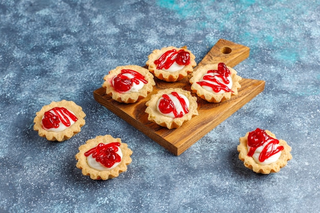 Tortine con ripieno di cioccolato bianco e marmellata di frutti di bosco sopra.