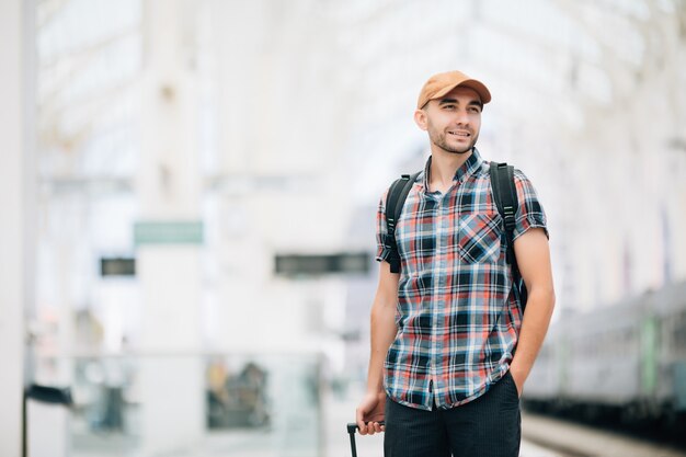 Tourist Man zaino in spalla e valigia per viaggiare alla stazione dei treni