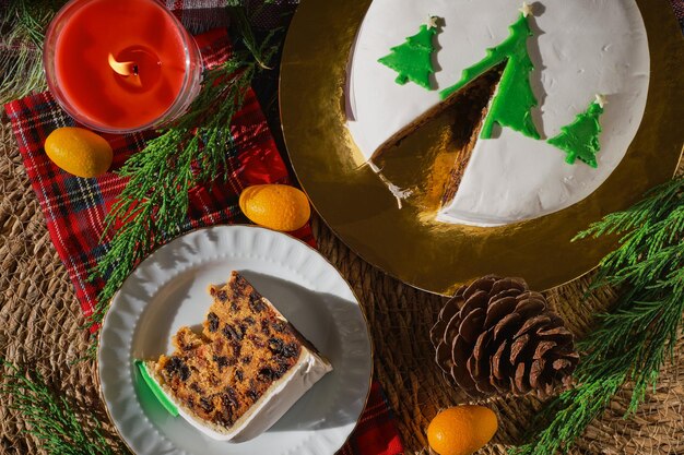 Tradizionale torta di Natale o budino sullo sfondo delle decorazioni natalizie vista dall'alto di una fetta di torta su un piatto Still life di cibo natalizio con frutta Torta inglese con marzapane