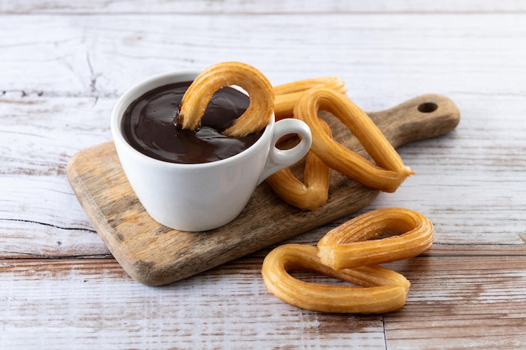 Foto gratuito tradizionali churros spagnoli con colazione di cioccolato caldo su un tavolo di legno