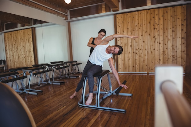 Trainer che aiuta una donna mentre pratica il pilates