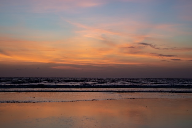 Tramonto con le onde che si infrangono sulla spiaggia