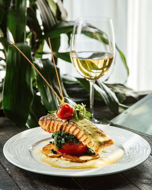 Trancio di salmone fritto posizionato sopra anelli di patate pomodoro e broccoli