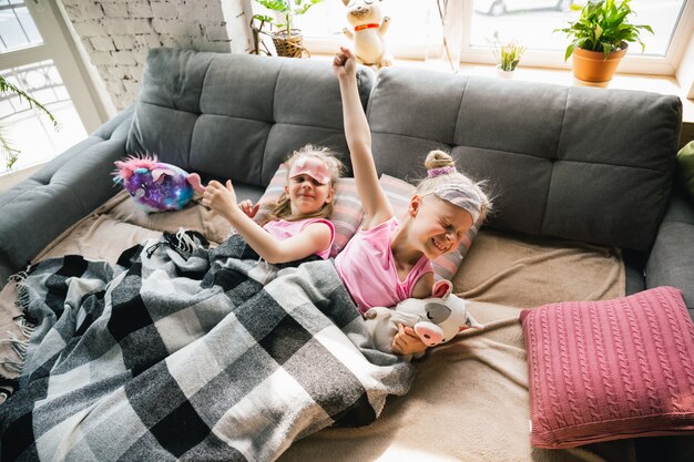 Tranquille bambine che si svegliano in una camera da letto in pigiama carino, stile casalingo e comfort