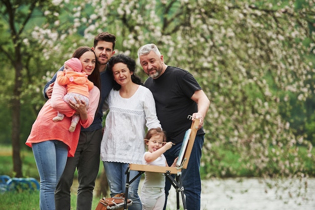 Trascorrere il fine settimana insieme. La famiglia si diverte nel parco. Giovane pittore che insegna a disegnare