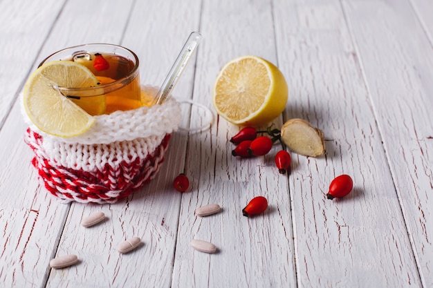 Trattare il freddo Tazza con tè caldo con limone e frutti di bosco si trova su un tavolo