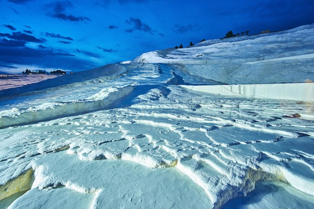 Travertini di Pamukkale in primo piano Cielo al tramonto e case illuminate