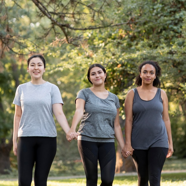 Tre amiche che tengono le mani al parco