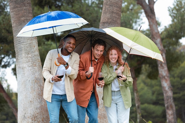 Tre amici che bevono vino sotto gli ombrelloni durante la festa all'aperto