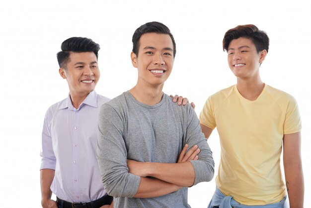 Tre amici maschii asiatici che posano insieme alla mano sulla spalla