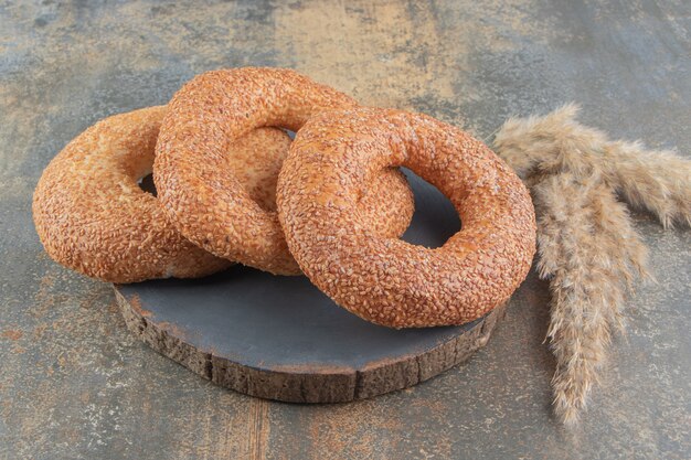 Tre bagel accanto a gambi di erba piuma su tavola di legno sul tavolo di marmo